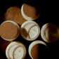 Five open white candles with cork stoppers arranged on a dark wooden surface under dramatic warm lighting.